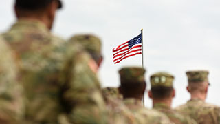 Military people and the U.S. flag in the background