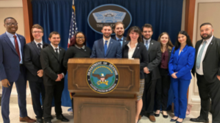 Students and faculty in front of the U.S. Department of Defense Podium.