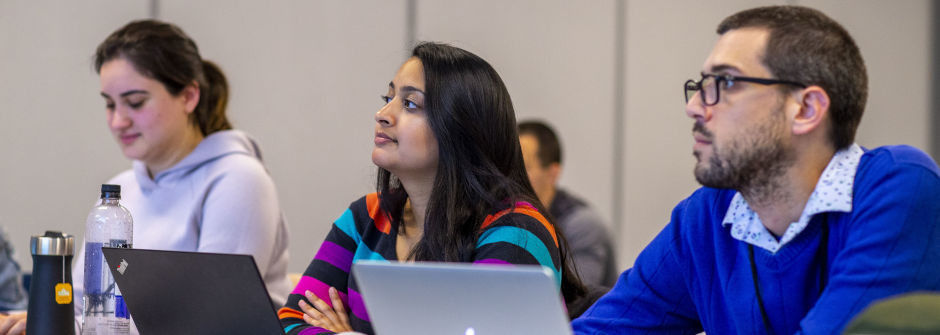 Students sitting with laptops in a classroom and paying attention in class