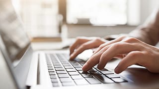 Hands typing on a laptop. 