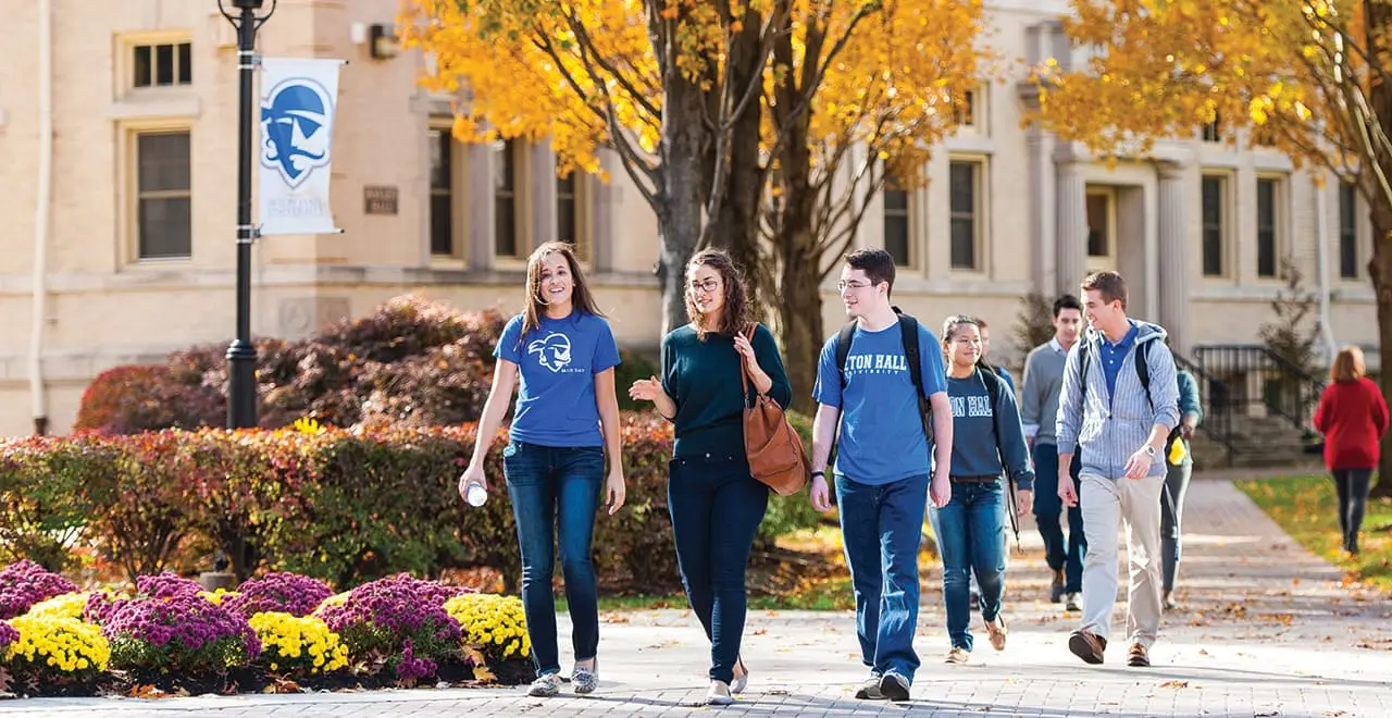 Image of students walking across the campus in the fall. 