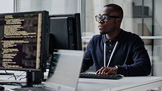 Computer programmer seen working at his desk.