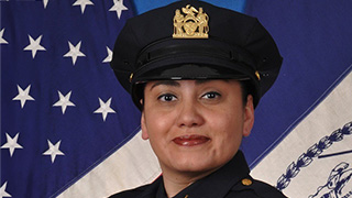 Detective Christine Casilla posing in front of a U.S. flag wearing her uniform