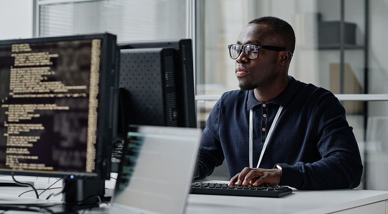 A young man working at a computer workstation in a computer lab.