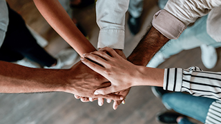 A group of people with their hands overlapping in the center.