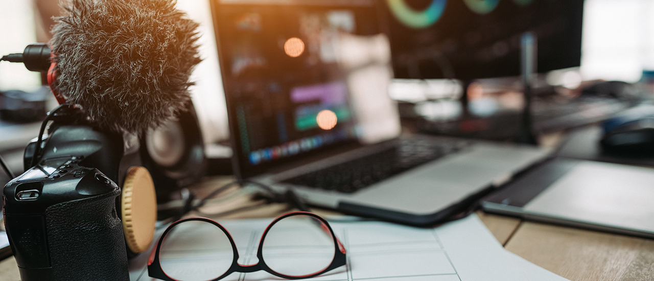 A desk with recording equipment, eyeglasses and storyboard papers