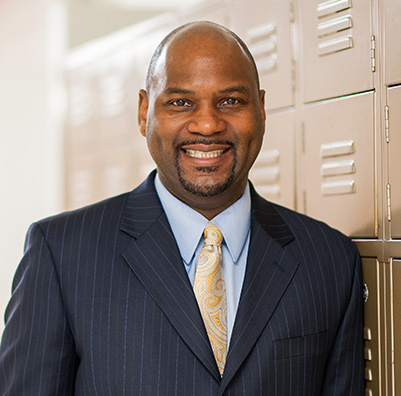 An educator standing in front of school lockers.