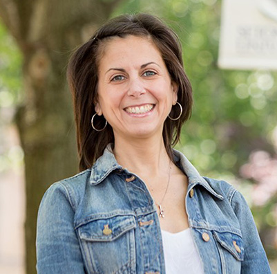 An educator standing in front of a tree on campus.