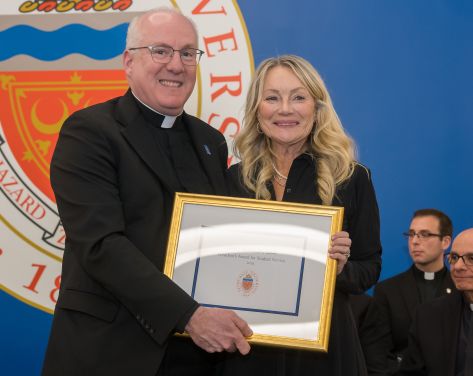 Monsignor Riley and Mary Mueller posing with an award