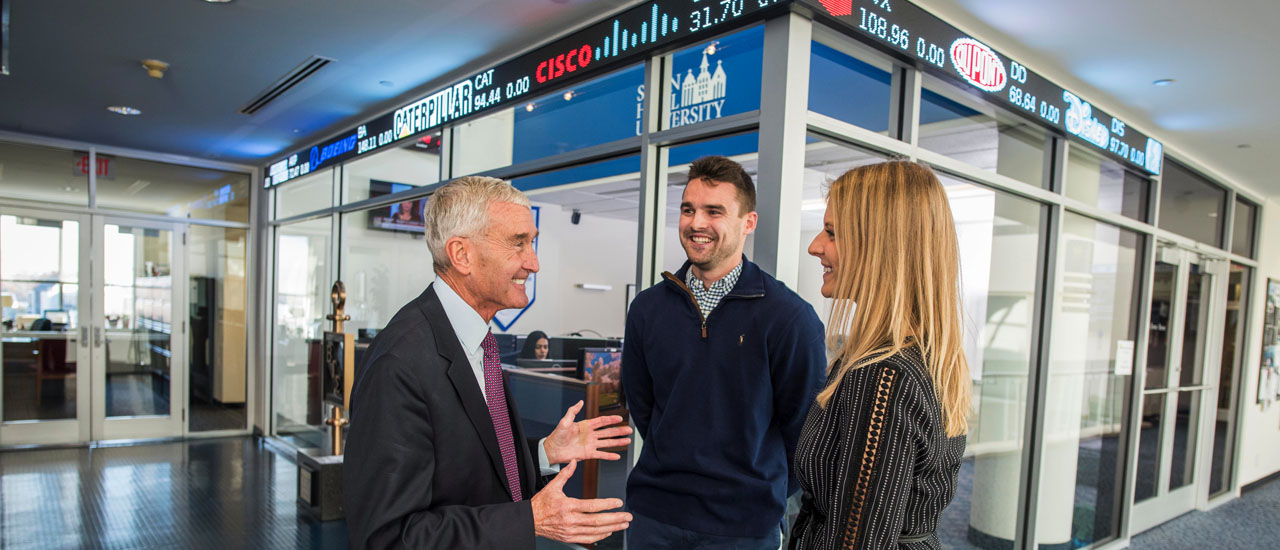 Mike Reuter and two grad students in front of Trading Room 